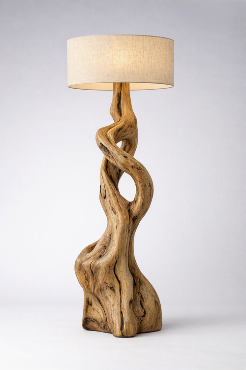 A sculptural floor lamp with a natural driftwood base and a drum shade, photographed on a light gray studio background.