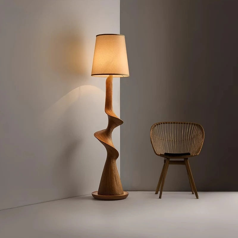 Wooden floor lamp with a wicker chair against a gray wall.
