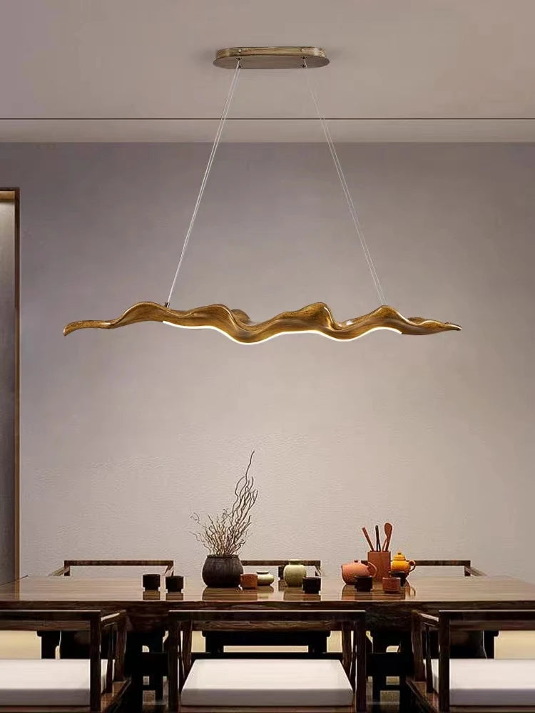 Modern wooden pendant light hanging above a dining table with a neutral background