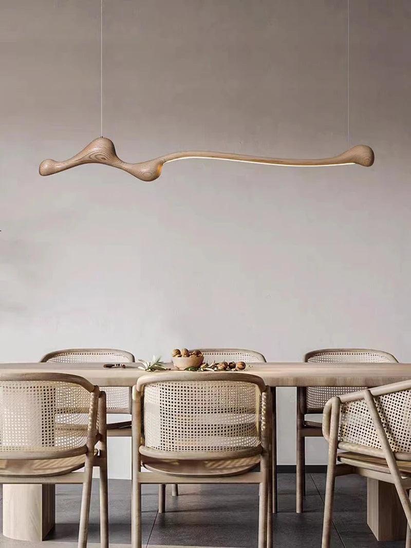 Dining area with a long table and wicker chairs, featuring a modern pendant light.
