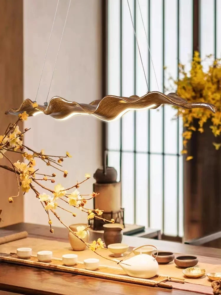 Decorative pendant light hanging above a table with floral arrangements and tea sets.