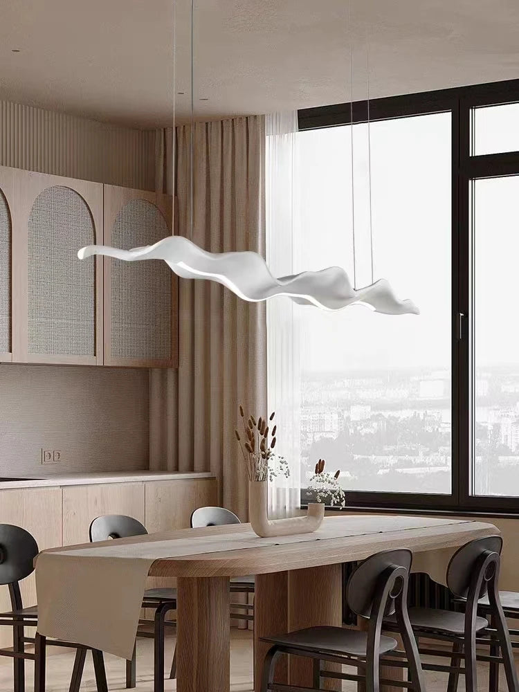 Modern kitchen with a long wooden dining table and chairs, featuring a unique pendant light.