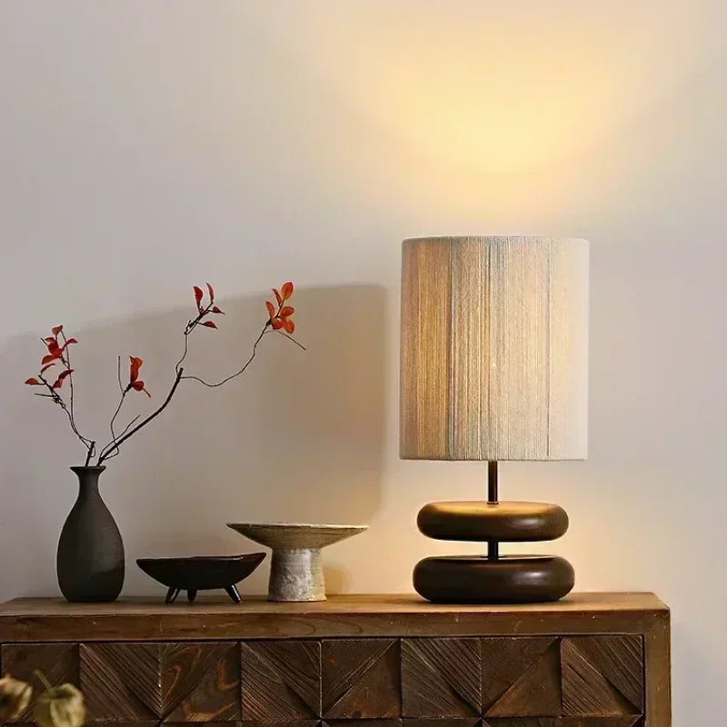 Modern lamp on a wooden console table with decorative items against a neutral wall.