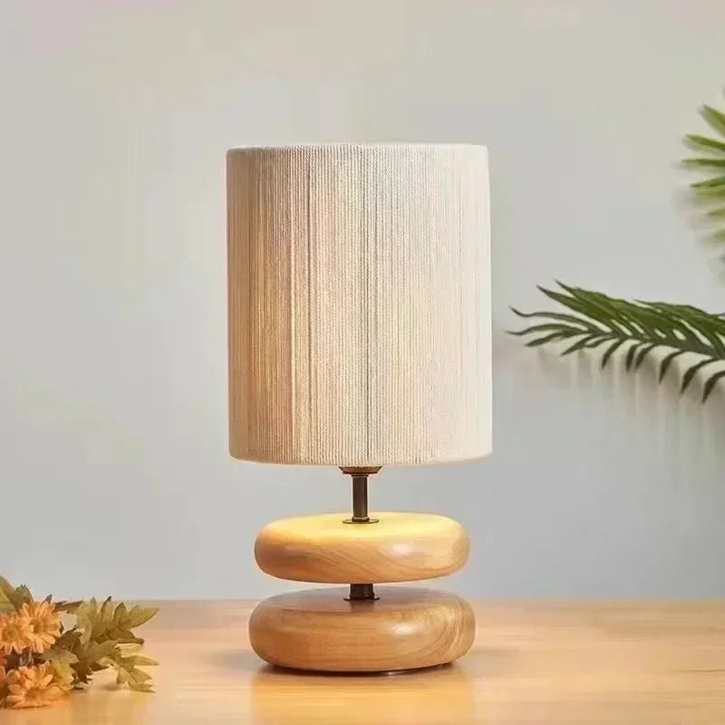Wooden table lamp with a textured shade on a wooden surface.